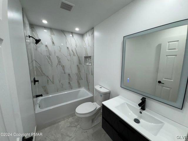 full bathroom featuring vanity, toilet, and tiled shower / bath