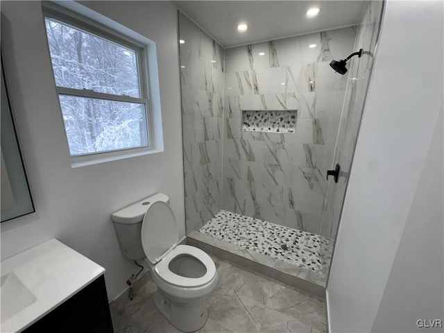 bathroom with tiled shower, vanity, and toilet