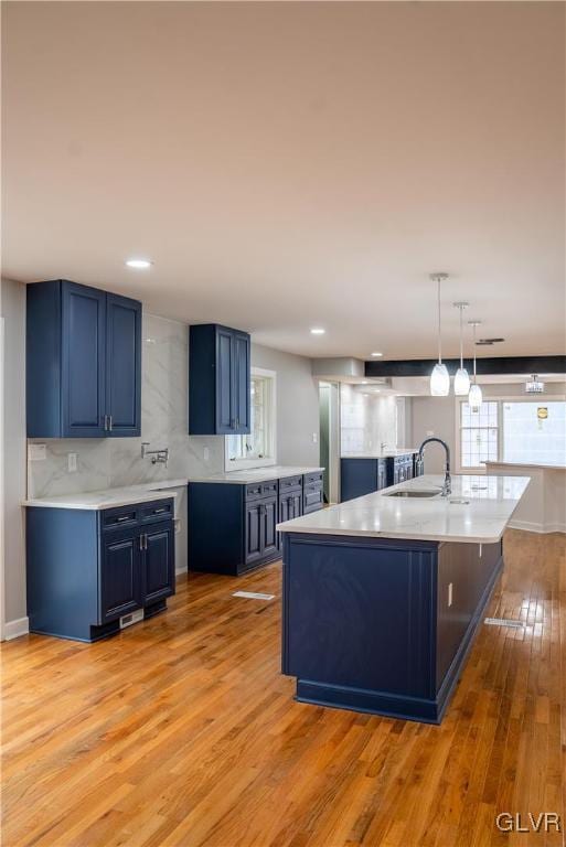 kitchen featuring decorative light fixtures, blue cabinets, light hardwood / wood-style floors, and sink