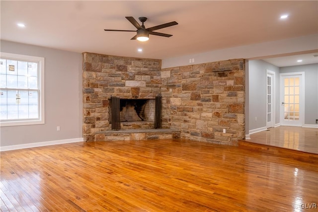 unfurnished living room featuring ceiling fan, wood-type flooring, and a fireplace