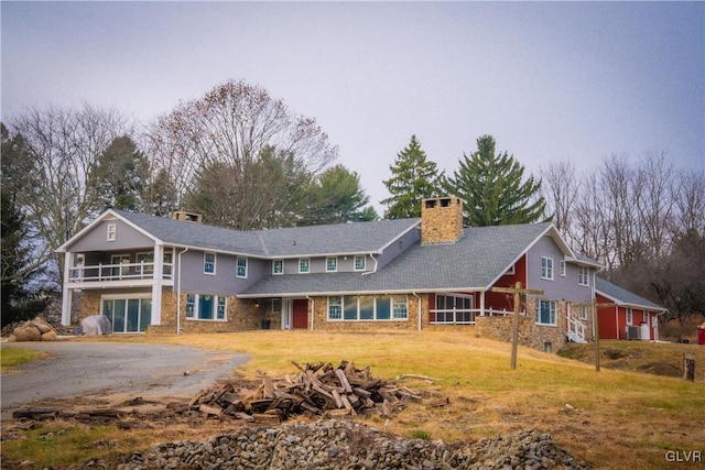 rear view of house with a yard, central AC, and a balcony