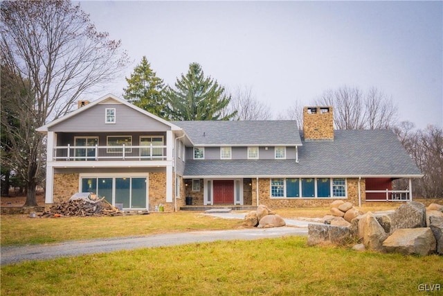 view of front of property featuring a balcony and a front yard