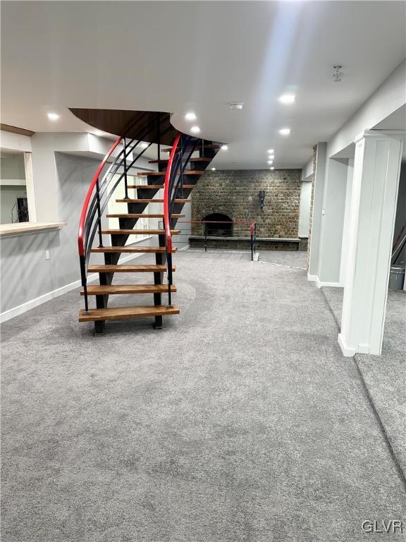 basement featuring carpet floors, a brick fireplace, and brick wall