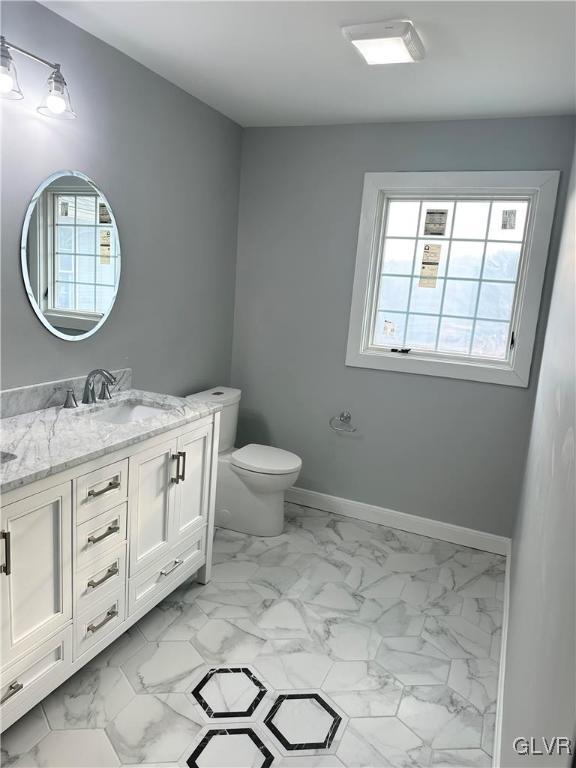 bathroom with a wealth of natural light, vanity, and toilet