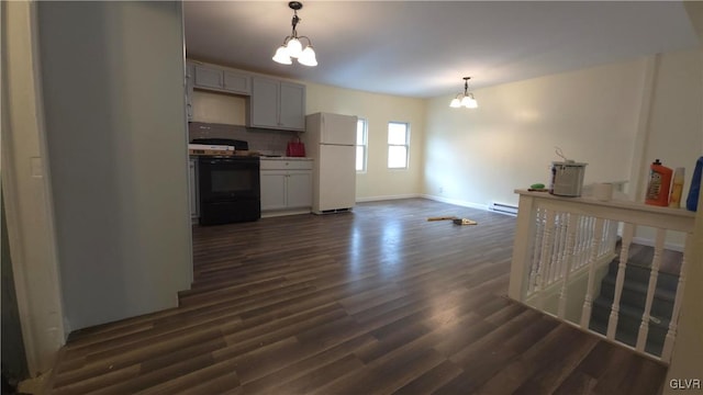 kitchen with dark wood-type flooring, hanging light fixtures, black range with electric cooktop, a notable chandelier, and white fridge