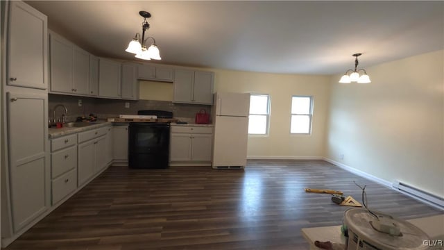 kitchen with black stove, sink, an inviting chandelier, white fridge, and dark hardwood / wood-style floors