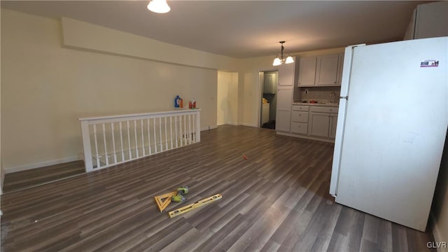 kitchen with decorative light fixtures, white fridge, dark wood-type flooring, and a chandelier