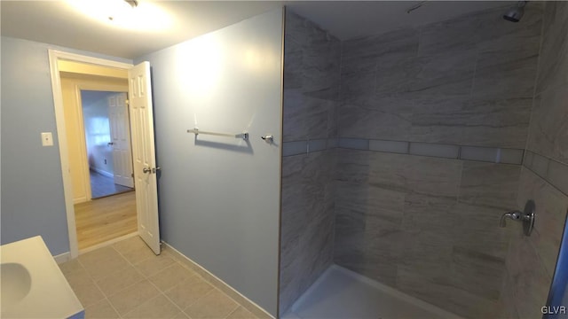 bathroom with a tile shower, tile patterned flooring, and vanity