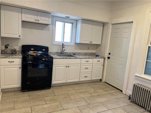 kitchen with white cabinets, sink, black gas range oven, light stone counters, and radiator heating unit