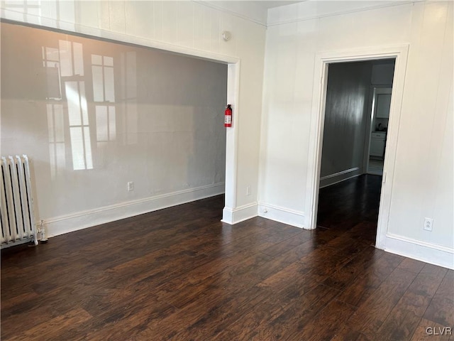 unfurnished room featuring radiator heating unit and dark wood-type flooring