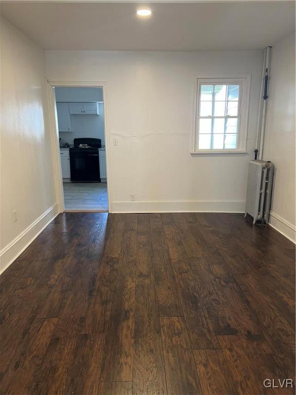 unfurnished room with dark wood-type flooring and radiator