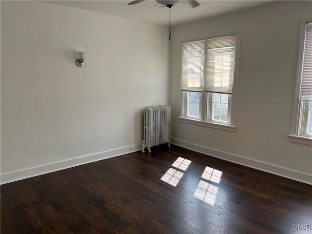 spare room with dark hardwood / wood-style flooring, radiator, and ceiling fan