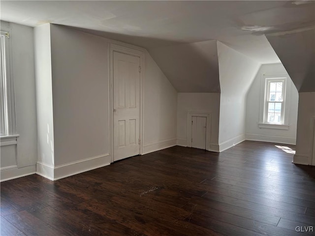 additional living space featuring dark wood-type flooring and lofted ceiling