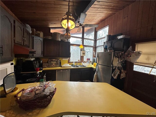 kitchen featuring pendant lighting, sink, wooden walls, appliances with stainless steel finishes, and wood ceiling