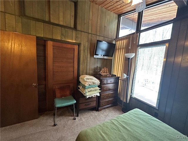 carpeted bedroom featuring wooden ceiling, wooden walls, and a closet