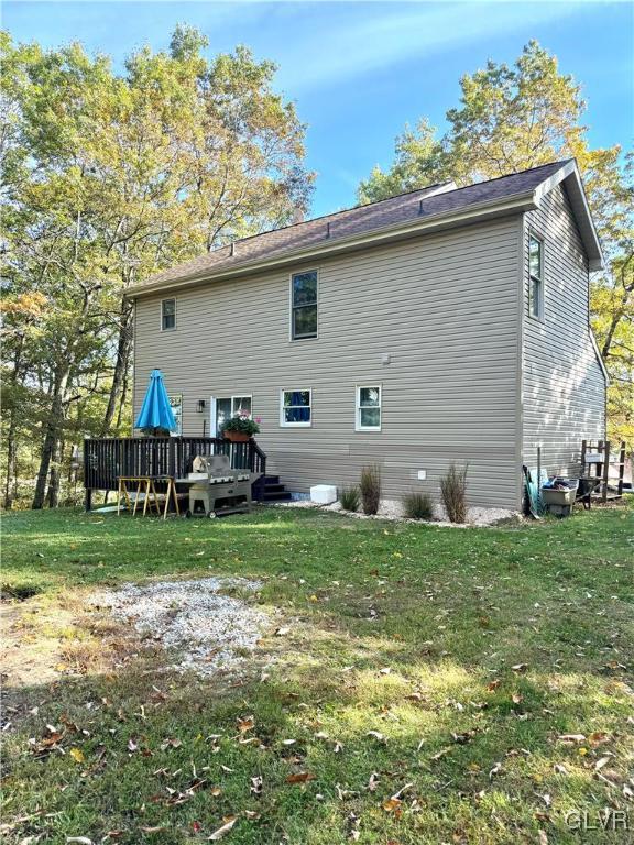 back of property with a lawn and a deck