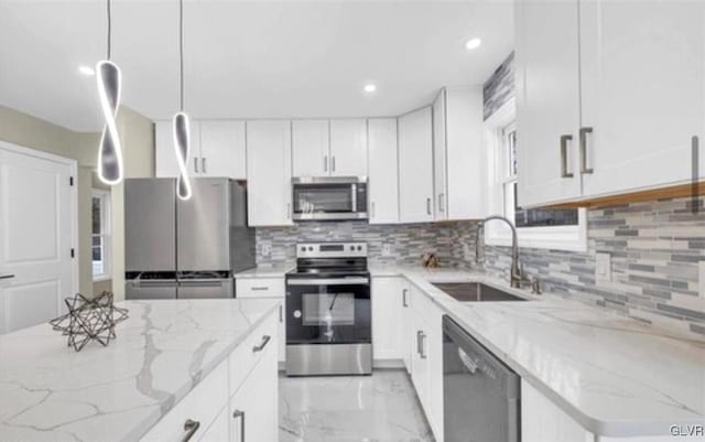 kitchen with sink, white cabinetry, light stone counters, and appliances with stainless steel finishes