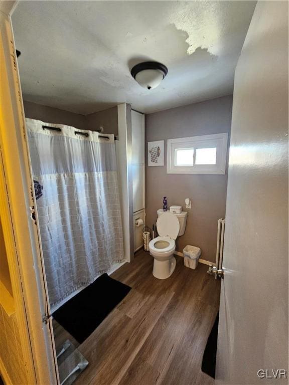 bathroom with a shower with curtain, hardwood / wood-style floors, and toilet