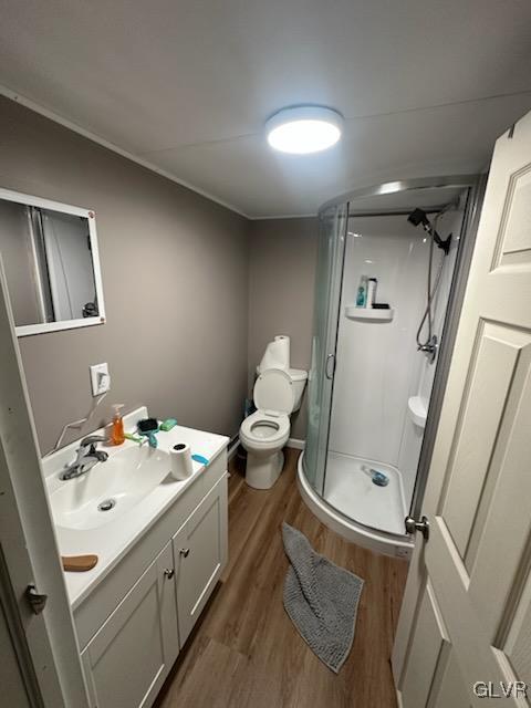 bathroom with hardwood / wood-style flooring, vanity, toilet, and an enclosed shower