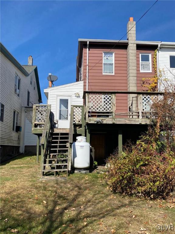 rear view of property featuring a lawn and a deck