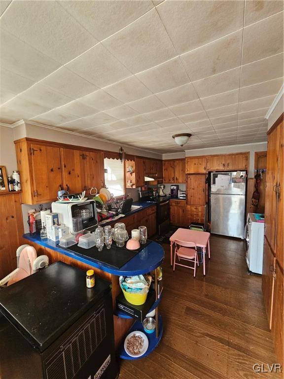 interior space featuring wood walls, black electric range, dark hardwood / wood-style floors, stainless steel fridge, and separate washer and dryer