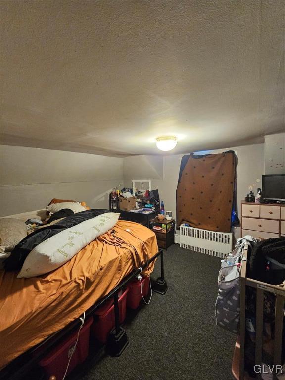 carpeted bedroom featuring radiator heating unit and a textured ceiling