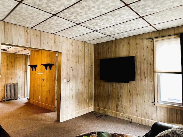 unfurnished living room featuring radiator, carpet, and wooden walls