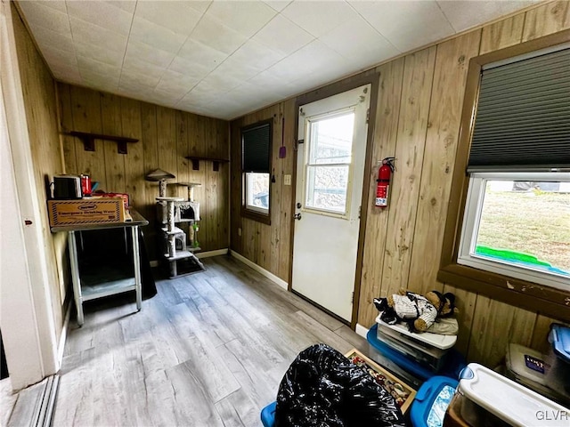 miscellaneous room with light hardwood / wood-style flooring and wooden walls