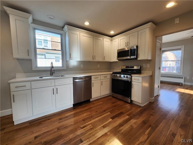 kitchen with white cabinets, radiator heating unit, sink, and appliances with stainless steel finishes