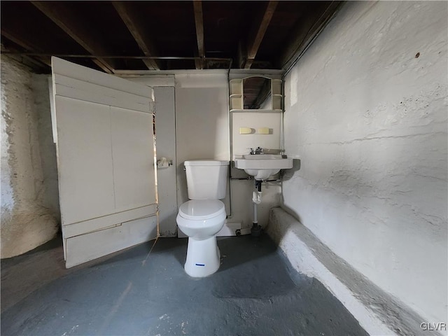 bathroom with concrete floors, toilet, and sink