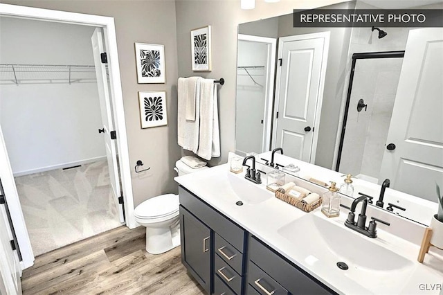 bathroom with vanity, wood-type flooring, a shower with shower door, and toilet