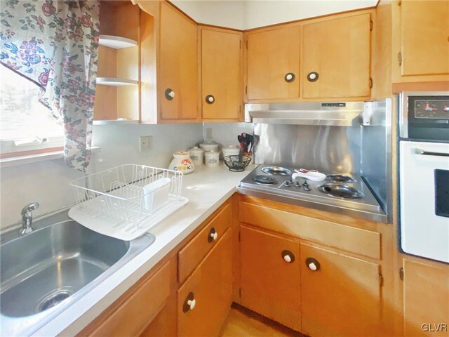 kitchen with white oven, stainless steel gas cooktop, and sink