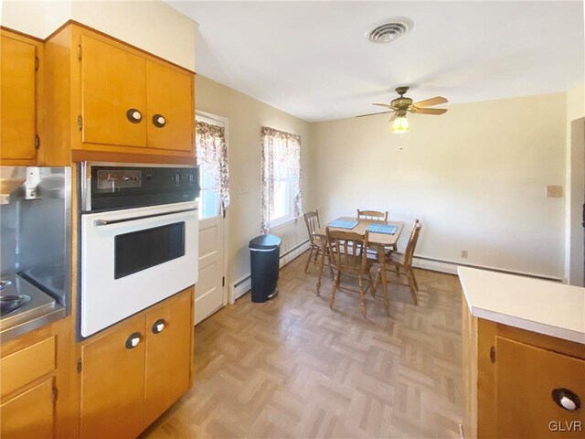 kitchen featuring light parquet flooring, a baseboard radiator, oven, and ceiling fan