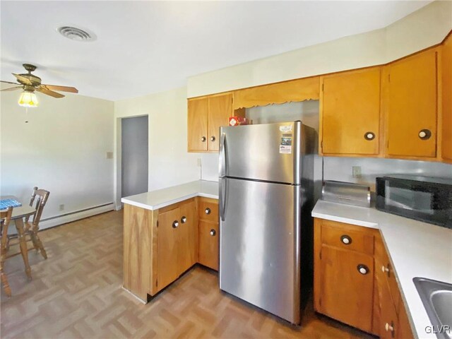 kitchen featuring ceiling fan, baseboard heating, kitchen peninsula, stainless steel fridge, and light parquet floors