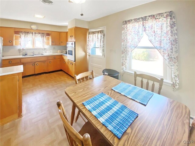 kitchen featuring stainless steel fridge, white oven, light parquet floors, and sink