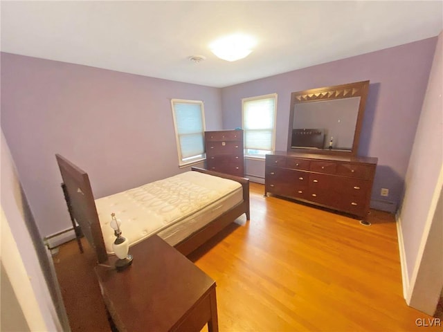 bedroom with light wood-type flooring and a baseboard radiator