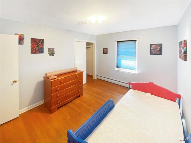 bedroom featuring a closet, wood-type flooring, and a baseboard radiator