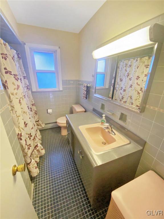 bathroom featuring tile patterned flooring, vanity, toilet, and tile walls