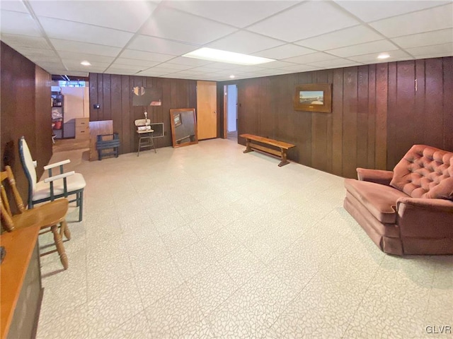 sitting room with a paneled ceiling and wooden walls