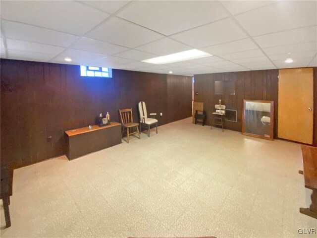 interior space featuring a paneled ceiling and wood walls