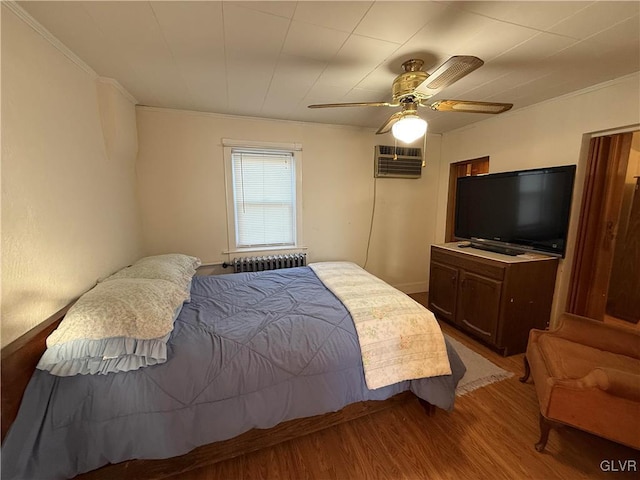 bedroom with light wood-type flooring, radiator, ceiling fan, crown molding, and an AC wall unit