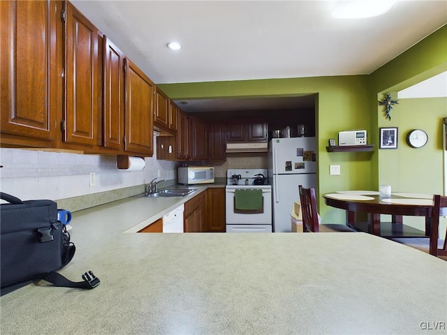 kitchen with kitchen peninsula, white appliances, backsplash, and sink