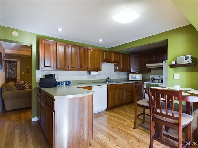 kitchen with decorative backsplash, sink, white appliances, and light wood-type flooring