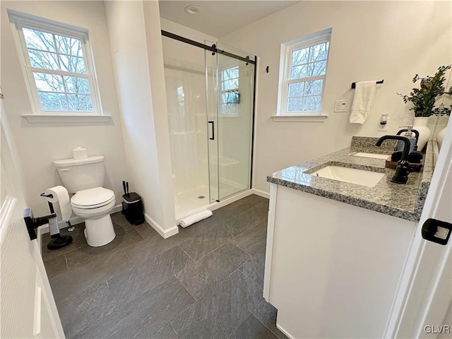 bathroom featuring toilet, vanity, a healthy amount of sunlight, and walk in shower