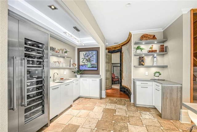 bar featuring sink, white cabinetry, crown molding, and light hardwood / wood-style flooring