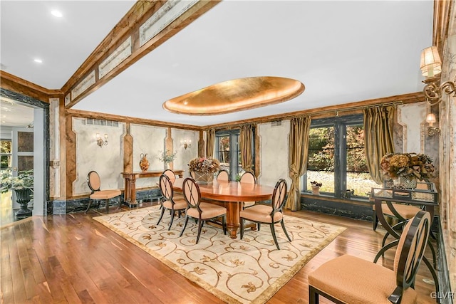 dining area with hardwood / wood-style floors and a raised ceiling