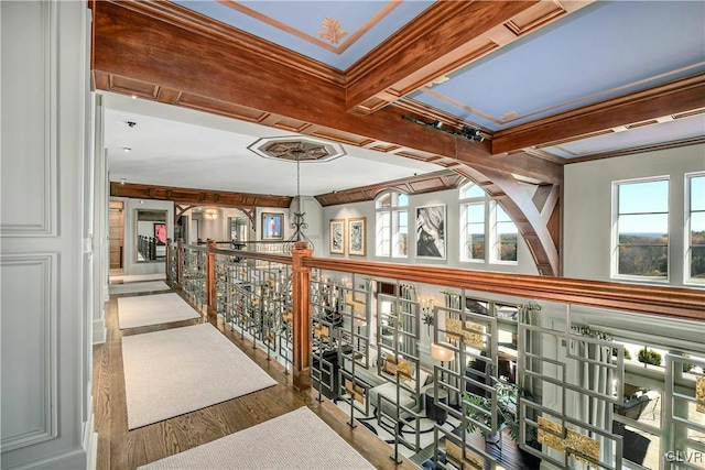 hall featuring beamed ceiling, ornamental molding, and light wood-type flooring