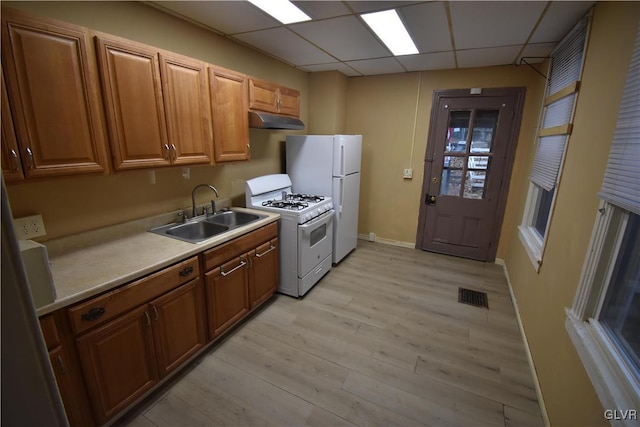 kitchen with white appliances, light hardwood / wood-style flooring, a drop ceiling, and sink