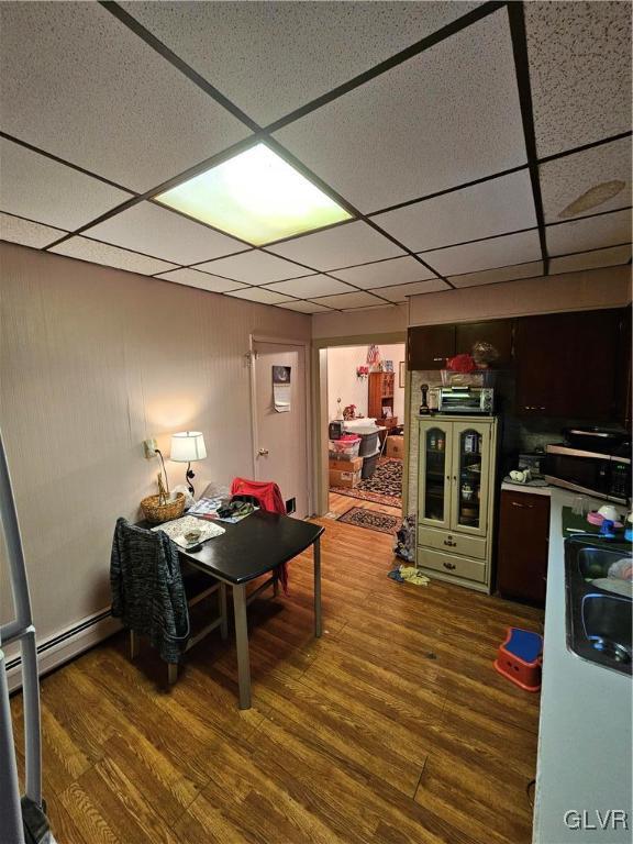 playroom with wood-type flooring, baseboard heating, a drop ceiling, and sink