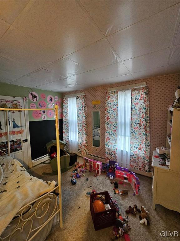 carpeted bedroom featuring a baseboard radiator and multiple windows